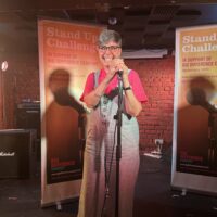 Dr Jacqui Norton stands on a stage behind a microphone.
