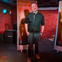 Miles Barnes stands on stage behind a microphone